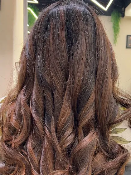 The rich texture of global highlights styled into soft curls. This shows the volume and dimension the color adds.