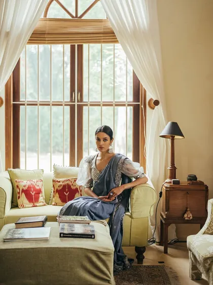 A wider version of an indoor lookbook shot. The composition includes more of the room's decor, framing the model and creating a complete lifestyle-oriented fashion image.