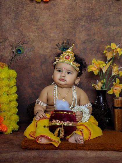 A sweet baby Krishna holding a pot of butter, looking directly at the camera. These close-up shots capture the adorable expressions of your little one.