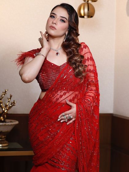 Another beautiful shot of the red draped saree, showing the intricate sequin pattern and the client's elegant jewelry.