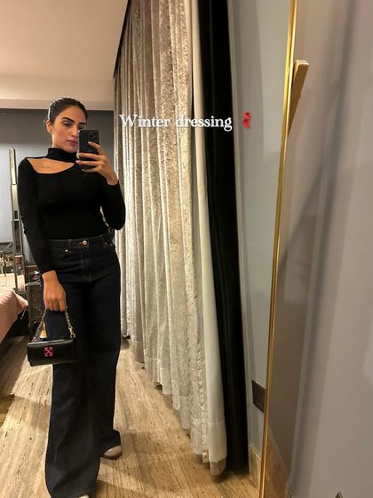 A sleek winter look with a black cutout turtleneck and dark wash wide-leg jeans. This is a great example of an elevated casual outfit for a night out.
