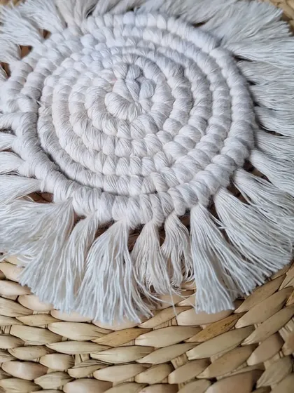 A close-up of my spiraled macrame coaster, showing the texture of the natural cotton cord and the soft fringe. It's all in the details.