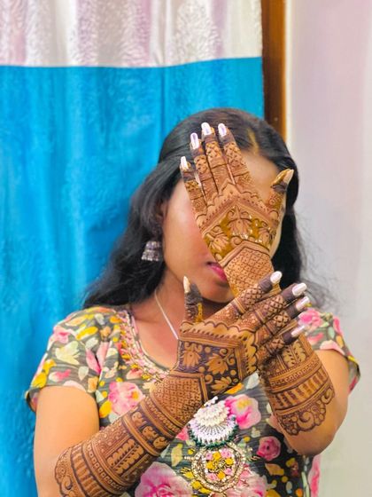 Another classic peek-a-boo pose, with the client's eyes visible between her henna-adorned fingers.