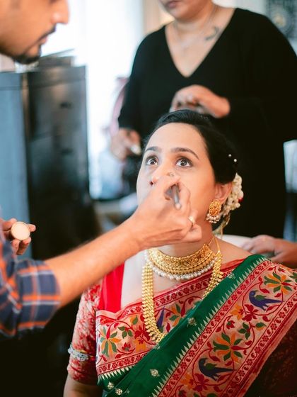 A behind-the-scenes moment of a Maharashtrian bride getting her makeup done. Our artist applies foundation, ensuring a flawless base that will last throughout the long wedding day.