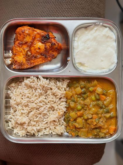 A balanced meal of brown rice, mixed vegetable curry, pan-fried fish, and a side of curd.