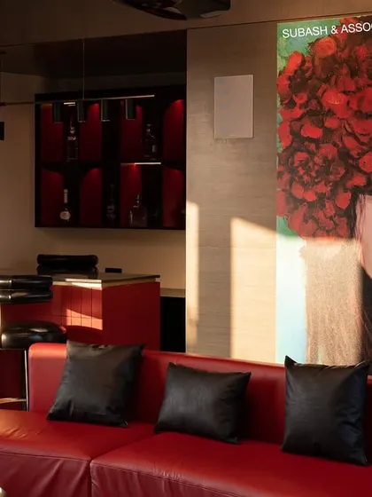 This entertainment lounge features a home theatre, a chic bar, and a bold black-and-red color scheme that exudes energy and sophistication.