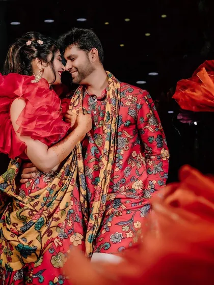 A romantic shot of the couple amidst the vibrant red decor of their Mehendi celebration.