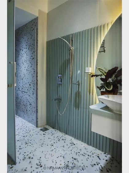 A view of the shower area in this modern bathroom. The combination of terrazzo and fluted tiles creates a space that is rich in texture and visual interest.