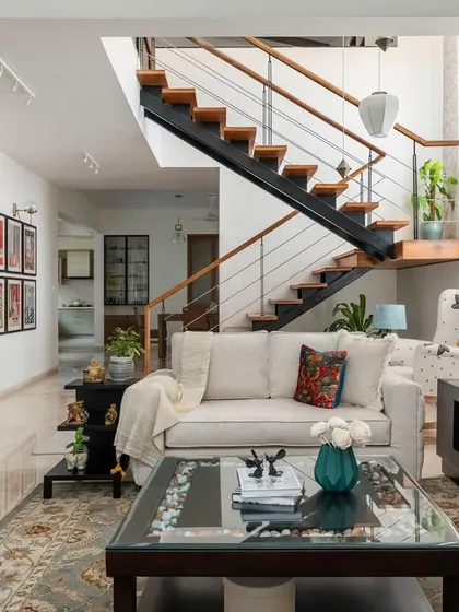 The interconnected living and dining area in 'House of Kismish', featuring a formal seating arrangement and a floating bookshelf with an integrated cabinet.