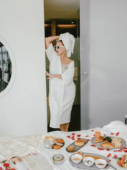 An artistic composition from the hotel lifestyle shoot. The model is framed in a doorway, creating a sense of mystery and elegance amidst the breakfast-in-bed scene.