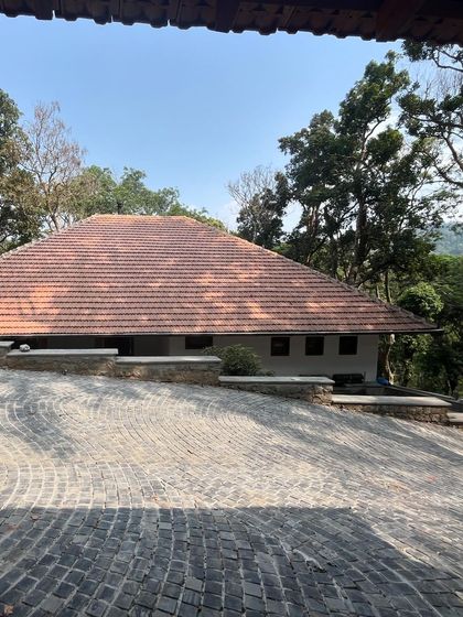 The cobblestone driveway of the Coorg holiday home, leading to a structure that sits low and respects the contours of the land.
