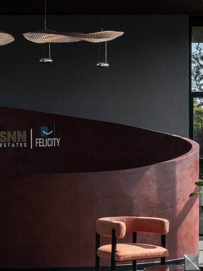 The SNN Estates marketing office features a striking curved reception desk made of reddish concrete, setting a bold and modern tone.