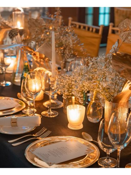 A close up of a menu card and place setting, illuminated by candlelight. We work with our clients to customize every element, including printed menus that guide guests through the curated culinary journey of the evening.