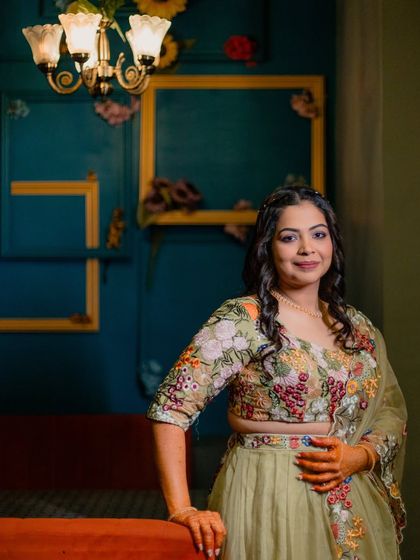 A stylish portrait of the bride at her Mehendi, posing against a colourful, artistic wall.