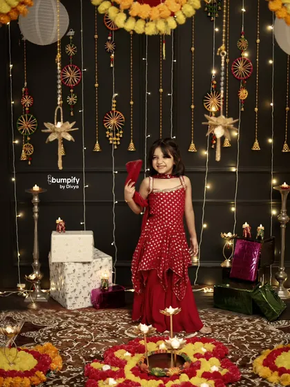 A full length portrait of this little girl in her stunning red outfit, enjoying the festive atmosphere of our Diwali studio setup.