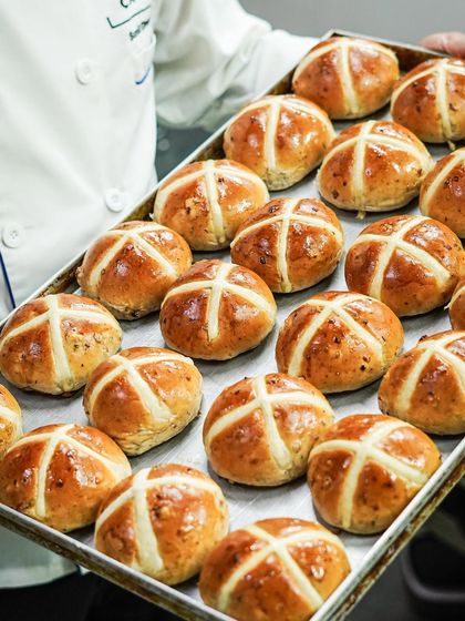A tray of our hot cross buns, fresh from the oven and beautifully glazed. They are a symbol of sharing and togetherness during the Easter season.