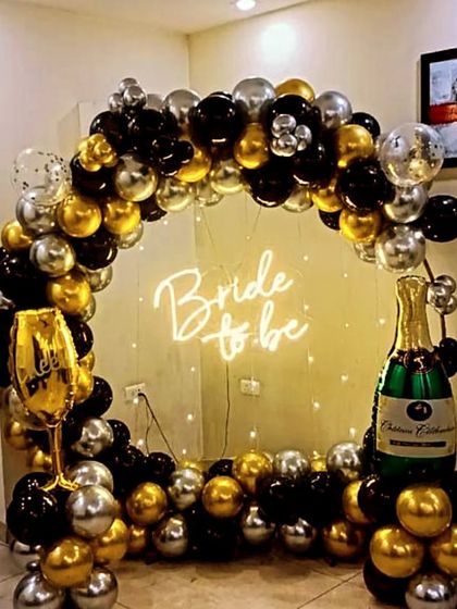 This black, gold, and silver 'Bride to be' theme is perfect for a nighttime celebration. The neon sign glows beautifully against the balloon arch, and the champagne and glass props add a fun, celebratory touch.