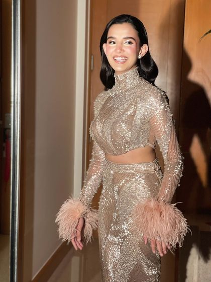 A happy, candid moment. The retro waves hairstyle is perfect for her embellished outfit with feathered cuffs, creating a complete look.