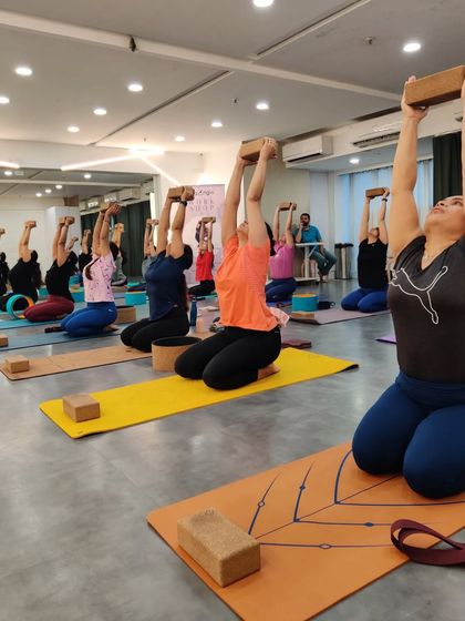 Lifting together. In our workshops, we focus on building strength and stability as a group, using props like blocks to maintain alignment and create a sense of shared effort.