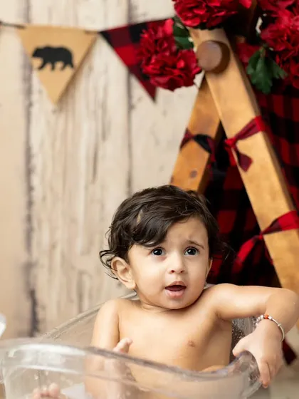 A look of surprise and wonder from the baby in the tub, surrounded by red flowers.