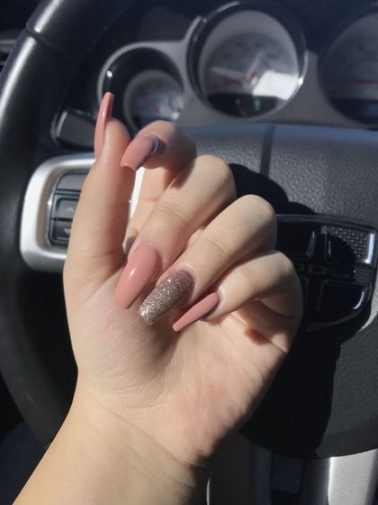 A beautiful set of long, coffin-shaped nails in a dusty rose color, with a single accent nail in a complementary rose gold glitter.