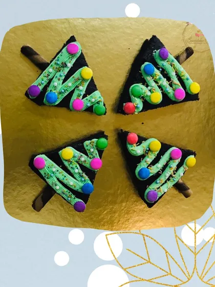 An overhead view of my Christmas tree brownies arranged on a platter. Each fudgy brownie is cut into a triangle and decorated with frosting and colorful candies, ready to be served at your festive gathering.