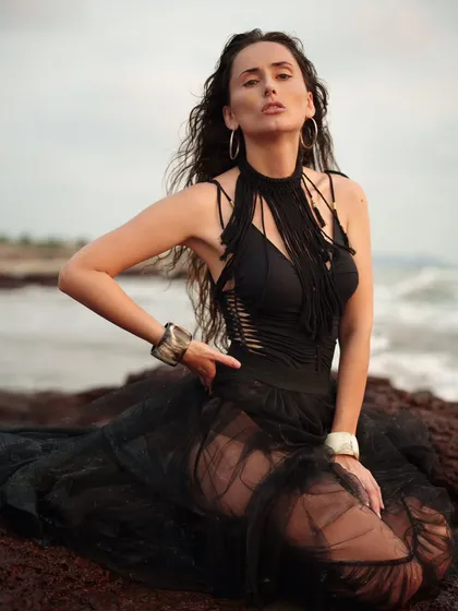 A kneeling portrait on the rocks, with a focus on the model's intense expression. The moody lighting and dramatic setting create a captivating image.