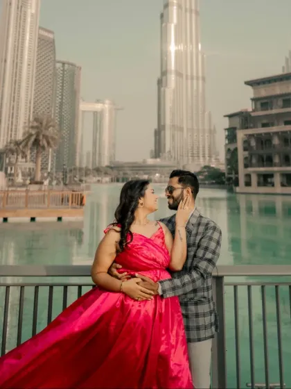 An intimate moment on a bridge in Dubai. The bright pink of the gown contrasts beautifully with the turquoise water, creating a vibrant and romantic pre-wedding portrait.