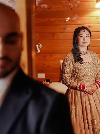 This shot teaches the art of the "reveal" or "first look" moment. We focus on composition, placing the groom in the foreground to create depth while keeping the bride in sharp focus, capturing her calm anticipation before the main event.