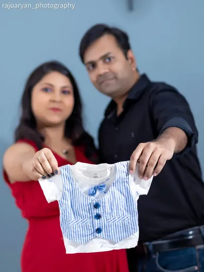 "Look what we got for you." This is a popular and heartwarming studio shot, where the parents-to-be proudly show off a tiny outfit for their baby. It’s a sweet preview of the new family member.