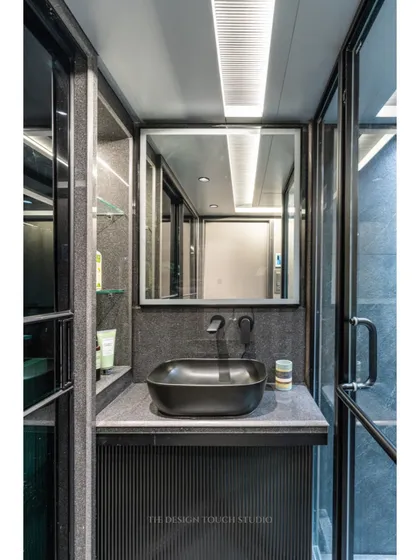 The vanity area in this bathroom includes a black vessel sink and a backlit mirror, creating a moody and luxurious atmosphere.