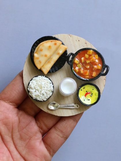 A miniature platter with rice, chapati, and two different curries.