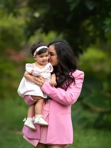 A sweet mother-daughter moment during an outdoor family session. The lush green background makes their pink outfits pop.