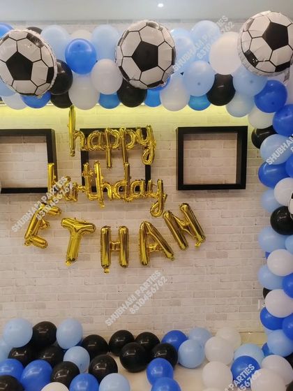 A football themed birthday party with soccer ball foil balloons and a blue, black, and white color scheme.