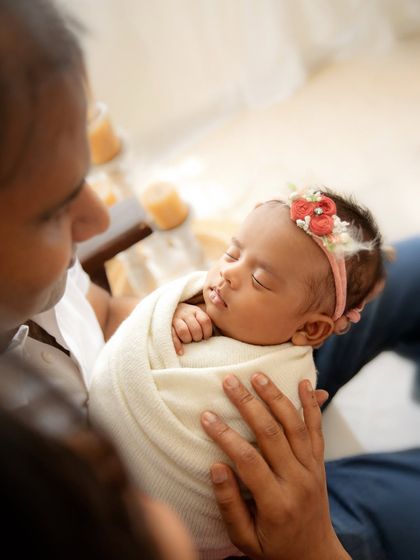 An over-the-shoulder view of a father holding his swaddled newborn, showing a different perspective of their bond.