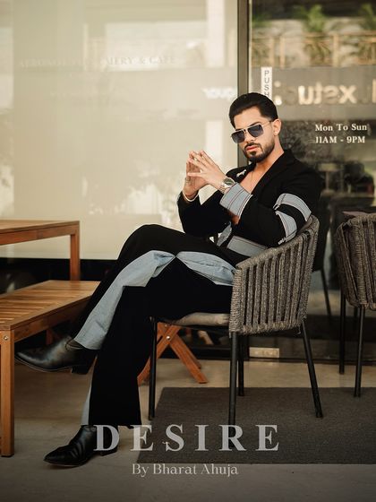 Another seated pose, this time showing the full length of the black and denim fusion co-ord set. It's a look that is both thoughtful and commanding.