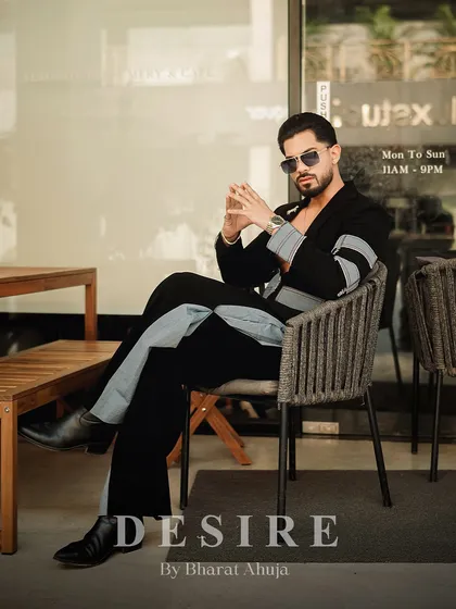 Another seated pose, this time showing the full length of the black and denim fusion co-ord set. It's a look that is both thoughtful and commanding.