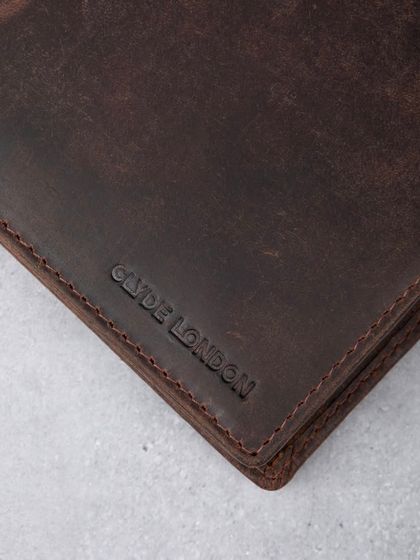 A macro shot of the debossed logo on a distressed leather wallet, showing texture and branding.