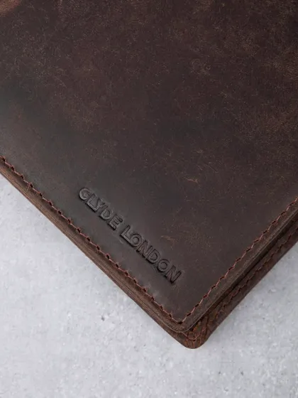 A macro shot of the debossed logo on a distressed leather wallet, showing texture and branding.