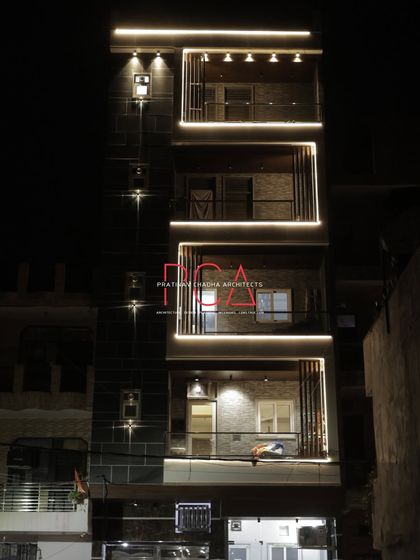 A complete view of 'The Cursive Abode' at night, showing the ground floor entrance and the full height of the illuminated structure.