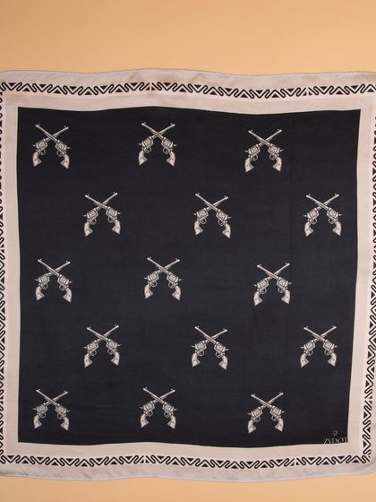 A flat-lay of the black pocket square with a crossed-pistols print, showing the full pattern.