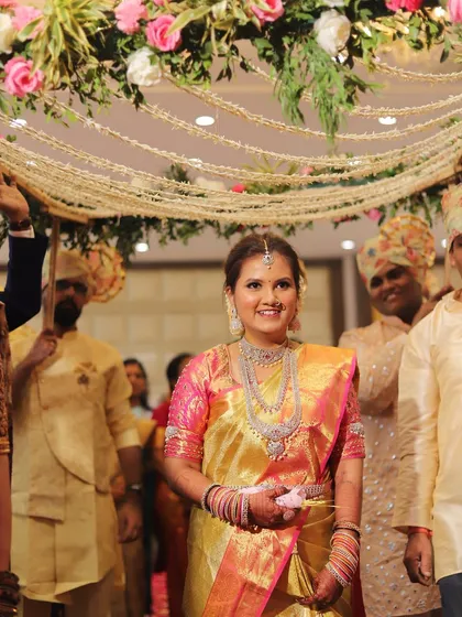 The bride's grand entrance in a stunning golden Kanjeevaram saree, her smile lighting up the room.