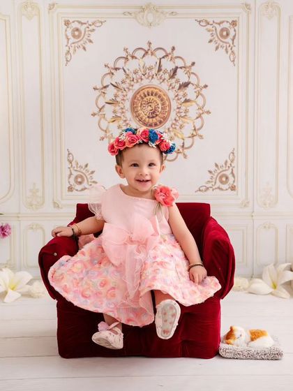 Little Miss Sunshine, shining so bright. This baby girl looks radiant and happy, sitting in a red armchair.