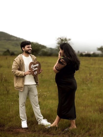 A playful and sweet surprise moment. The dad-to-be holds up the "Coming Soon" sign, and her happy, surprised reaction is what makes this shot so genuine and special.