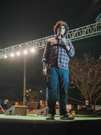 A full-length shot of Joel D'souza on the large stage at IIIT Hyderabad.