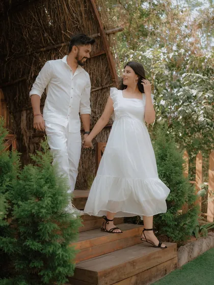 A classic pre-wedding pose, holding hands and walking down a rustic wooden staircase. The all-white outfits create a fresh and timeless look for this romantic shoot.