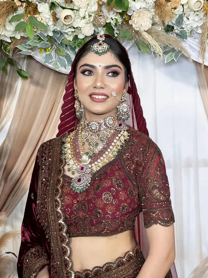 A close-up of this bride's happy and glowing face. The makeup features a beautiful blend of pink and maroon on the eyes, paired with heavy traditional jewelry for a truly royal feel.