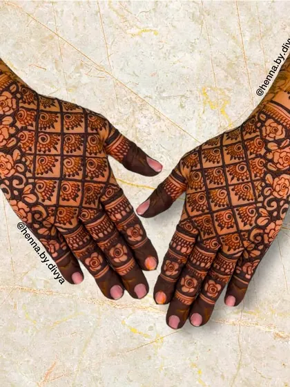 A very dense and detailed back-hand design with a floral grid pattern. The cuff features a band of jhumkas, adding a traditional element to the intricate layout.