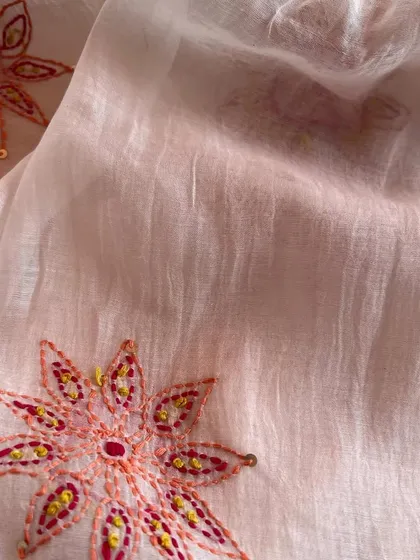 This hand-embroidered Mul Chanderi features delicate floral medallions in warm, earthy tones. It's a fabric that tells a story of artisanal craftsmanship.