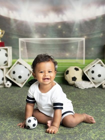 Goal! This little football star is all smiles on his custom soccer field set. It's the perfect theme for a family of sports lovers.